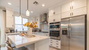 A modern kitchen with white cabinetry, stainless steel appliances, and pendant lighting. - @marbella Lane -amazing 5BR Home in Rancho Mission (San Juan Capistrano)