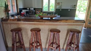 Una cocina con una isla de madera, cuatro taburetes, un ventanal y una puerta.