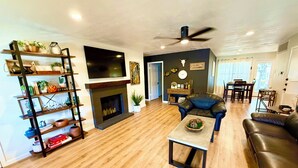 A spacious living room with a fireplace, a television, a ceiling fan, and a dining area with a table and chairs. - Charming 3-bedroom Georgetown house close to Square. Long term stays welcomed. (Georgetown)