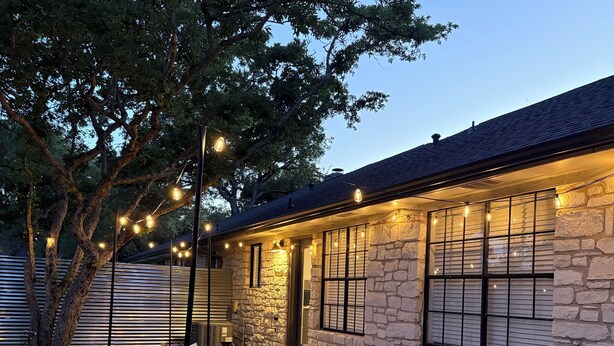 An outdoor patio with stone walls, a table with chairs, and string lights. - Charming 3-bedroom Georgetown house close to Square. Long term stays welcomed. (Georgetown)