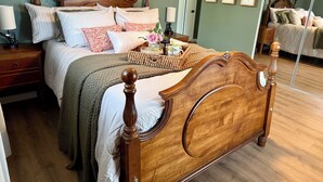 A neatly made bed with a wooden headboard, a bedside table with a lamp, and a mirror on the wall. - Charming 3-bedroom Georgetown house close to Square. Long term stays welcomed. (Georgetown)