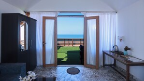 A room with a view of the sea, a dark wardrobe, a small table with a vase, and a green mat on the floor. - Silent waves (Canacona)