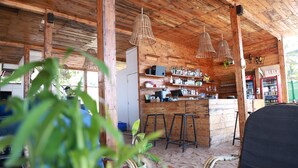 A rustic wooden interior with a bar area, wooden stools, and a refrigerator. - Silent waves (Canacona)