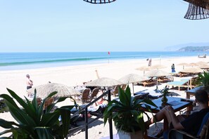 Un cadre idyllique au bord de la plage, avec des chaises longues, des parasols et une vue sur l’océan.