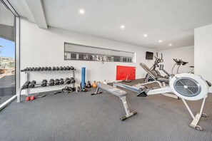A modern gym with exercise equipment, a wall-mounted mirror, and a large window.