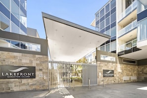 A modern building with a glass facade, a stone wall entrance, and a sign reading 'LAKEFRONT KINGSTON ISLAND'.