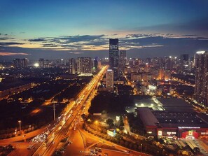 A cityscape at dusk with illuminated buildings and a busy highway.