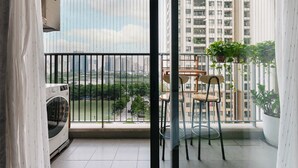 Ein Balkon mit Waschmaschine, zwei Stühlen und einem Tisch mit einer hängenden Pflanze.