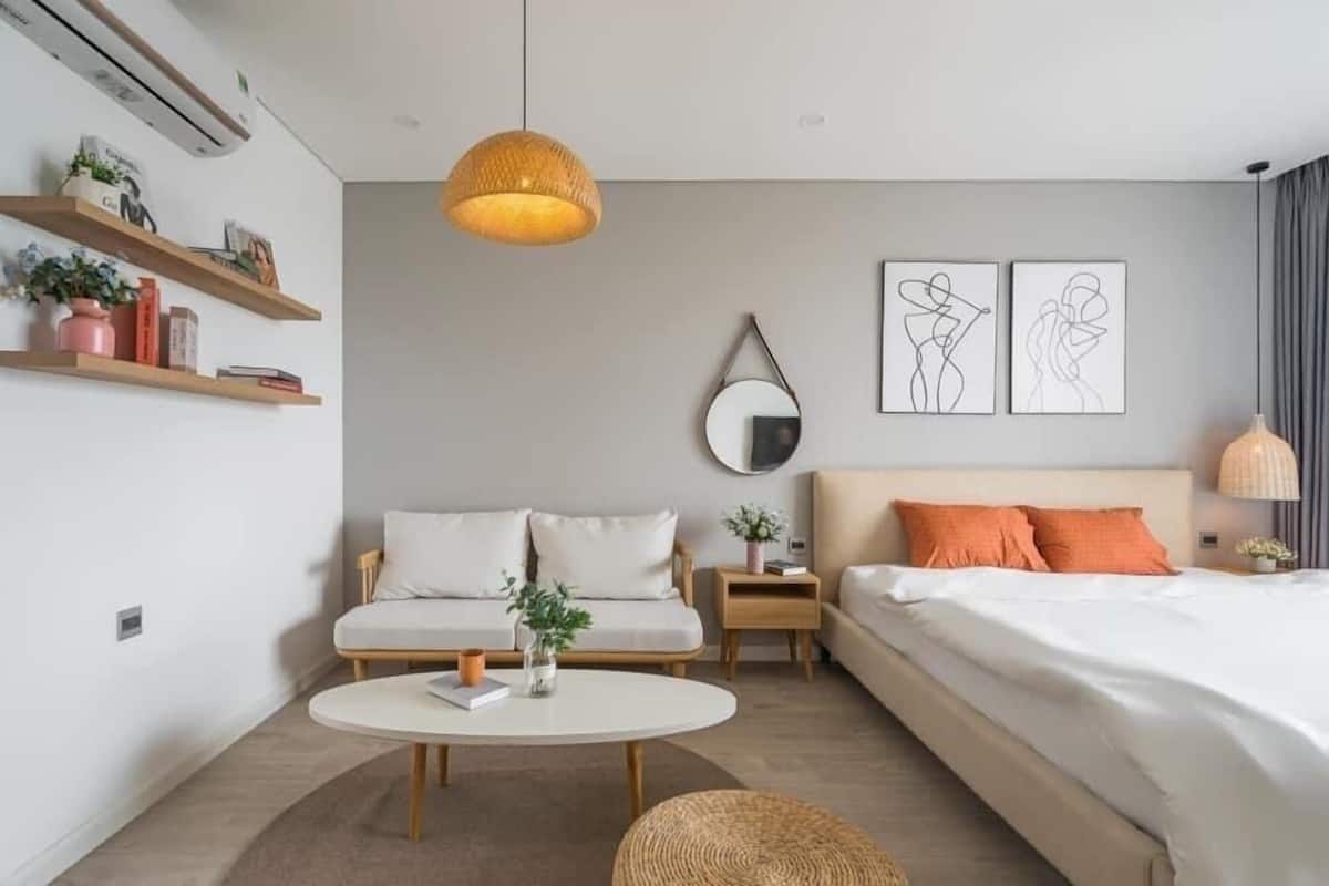Een moderne hotelkamer met een bank, een bed, een ronde salontafel en een hanglamp.