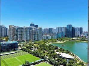 Un paysage urbain avec de hauts immeubles, un parc avec un lac et un terrain de sport.