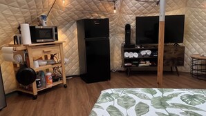 A cozy, well-lit tent-style room with a bed, a small kitchenette, a TV, and a wooden cabinet. - Cozy Yurt in perfect Austin with AC, Free Wifi, free Parking & jacuzzi use (Austin)