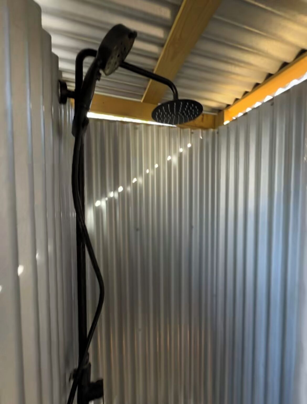 A shower with a handheld showerhead mounted on a wall.