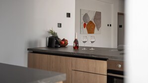 A modern kitchen with a marble countertop, wooden cabinets, and a minimalist artwork on the wall. - LE BOUQUET LUXURY SUITES  (Nicosia)