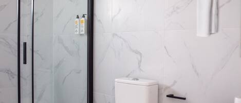 A modern bathroom with a toilet, a glass shower enclosure, and a marble-patterned wall.