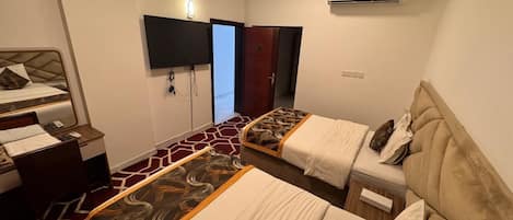 Een hotelkamer met twee bedden, een bureau, een stoel, een televisie en een airconditioner.
