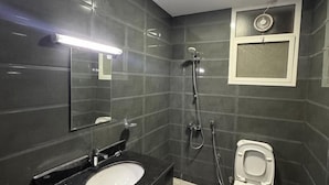 Une salle de bain équipée d’un lavabo, d’un miroir, de toilettes et d’une douche.