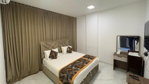 Une chambre d’hôtel comprenant un lit, un bureau, une chaise, une télévision et un miroir.