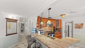 Una cocina con encimera de mármol, armarios de madera e iluminación colgante.