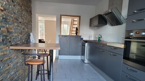 A modern kitchen with a brick wall, a wooden table, and bar stools. - Spacious duplex at Matthieu's. Sleeps 1 to 6. (Remiremont)