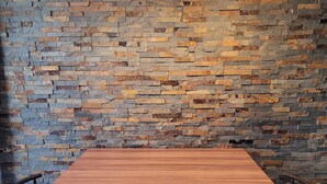 A wooden table with two stools, set against a stone wall with hanging lamps. - Spacious duplex at Matthieu's. Sleeps 1 to 6. (Remiremont)