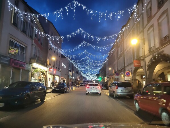 Une rue bordée d’immeubles, décorée de guirlandes lumineuses.