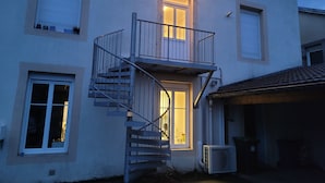 A two-story building with a central staircase, a garage, and a balcony. - Spacious duplex at Matthieu's. Sleeps 1 to 6. (Remiremont)