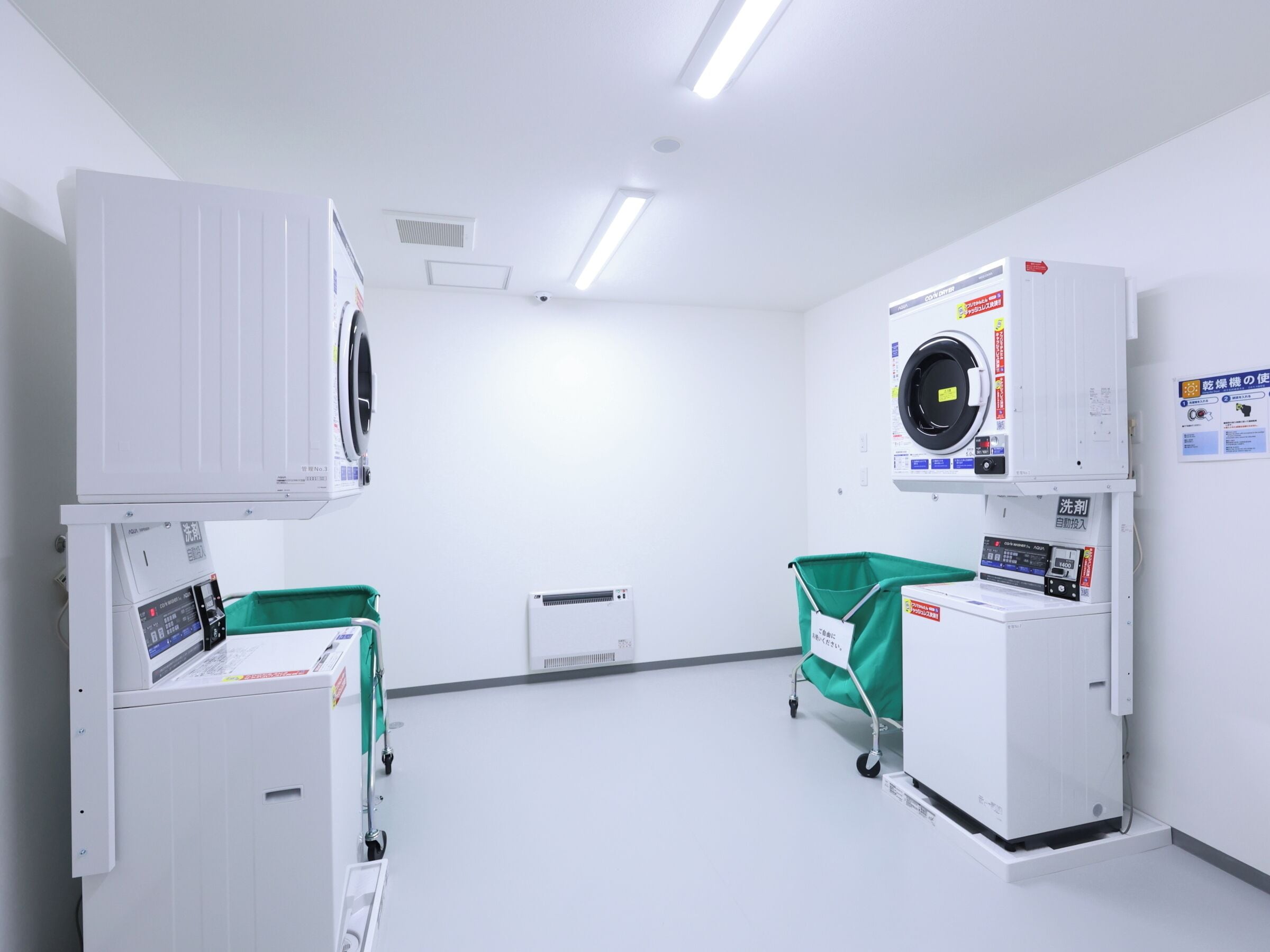 A clinical setting with medical equipment, including a washing machine, a sterilizer, and a cart with a green cover.