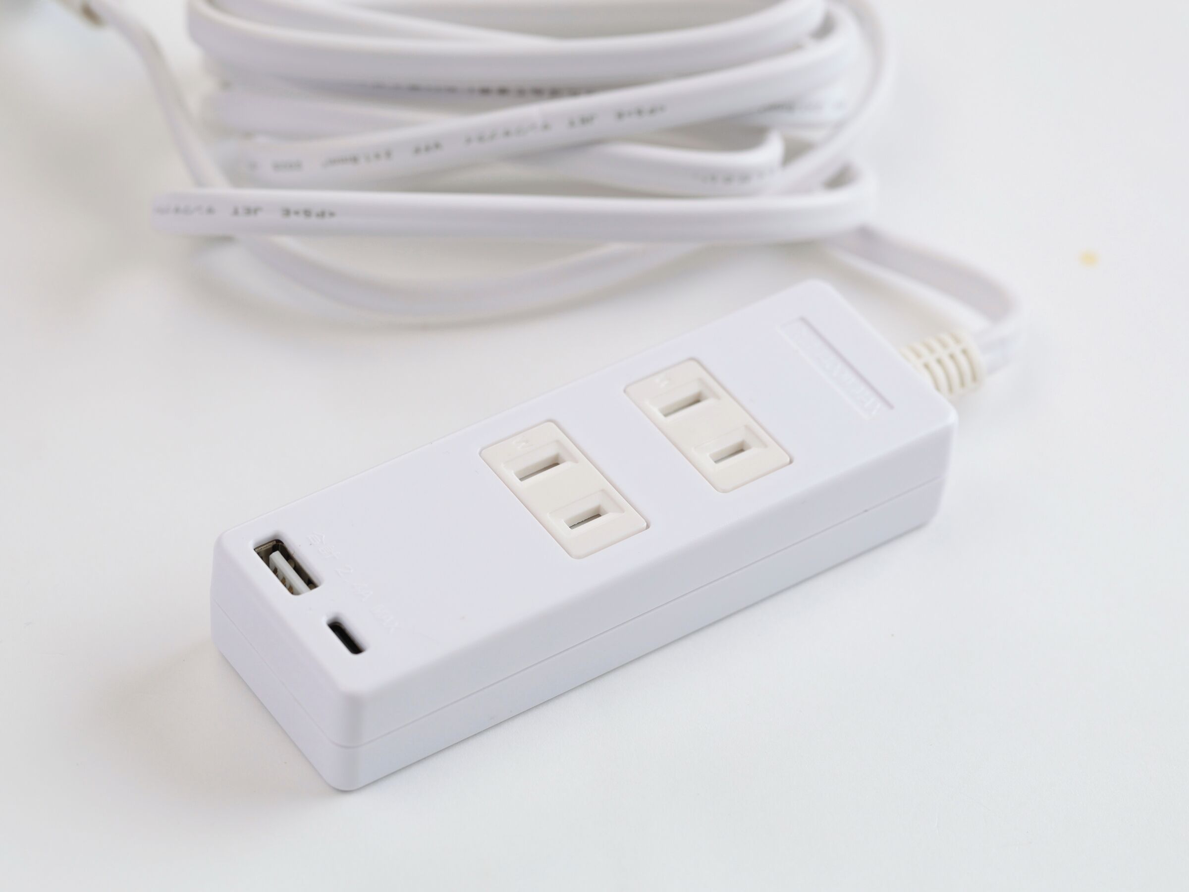 A white power strip with two USB ports and a standard electrical outlet.