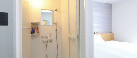 A hotel room with a shower, a bed, and a bedside table.