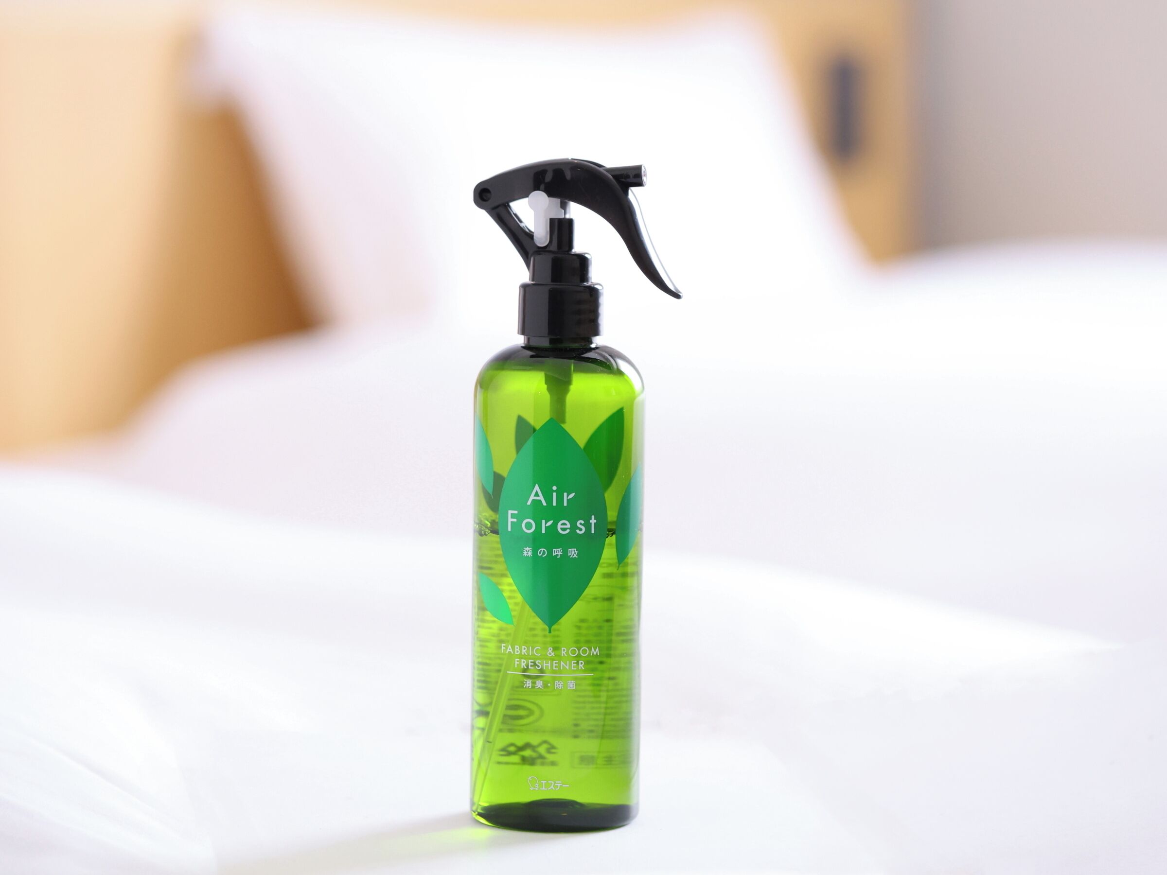 A bottle of Air Forest fabric and room freshener on a bed.