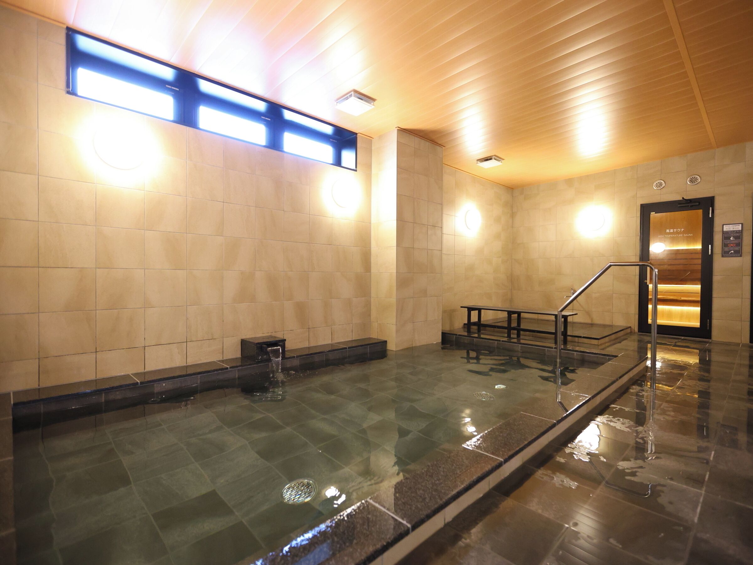 A clean, well-lit indoor swimming pool area with tiled walls and a wooden ceiling.