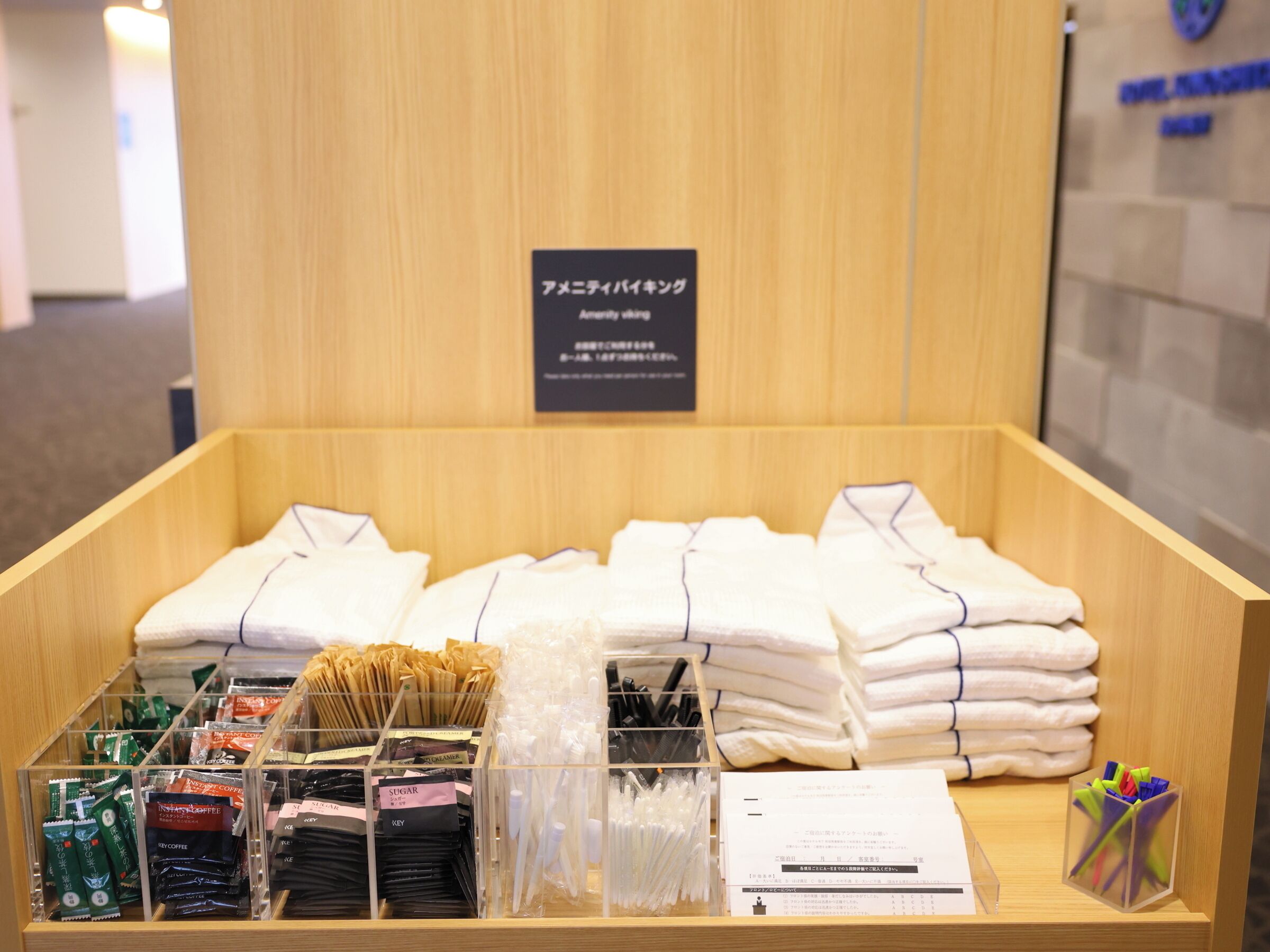 Una presentación de camisas blancas dobladas con cuidado y varios productos de café en una caja de madera.