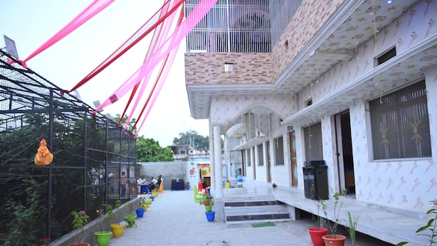 A courtyard with a brick building, potted plants, and a metal fence. - Shri Sita Vallabh Padchhaya (Ayodhya)