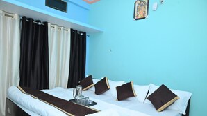 A hotel room with a bed, curtains, pillows, a tray with a teapot, and a wall clock. - Shri Sita Vallabh Padchhaya (Ayodhya)