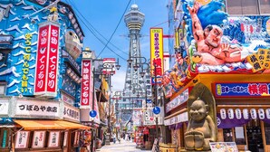A bustling street with various shops and a prominent statue of a figure. - [ 303 ] Twin Japanese-style room with kitchen, bathroom and washing machine, 2 min. from the nearest station, along the airport line. (大阪市)