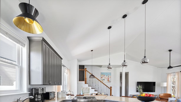 A modern kitchen with grey cabinets, stainless steel appliances, and a wooden floor.