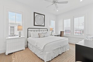 A bedroom with a bed, a nightstand, a desk, and a window with blinds. - Grayt Digs by AvantStay | Next to Beach, Oceanview (Santa Rosa Beach)