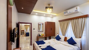 A hotel room with a bed, a television, an air conditioning unit, a mirror, a desk, and a window with curtains. - Chechus Beach Walk (Varkala)