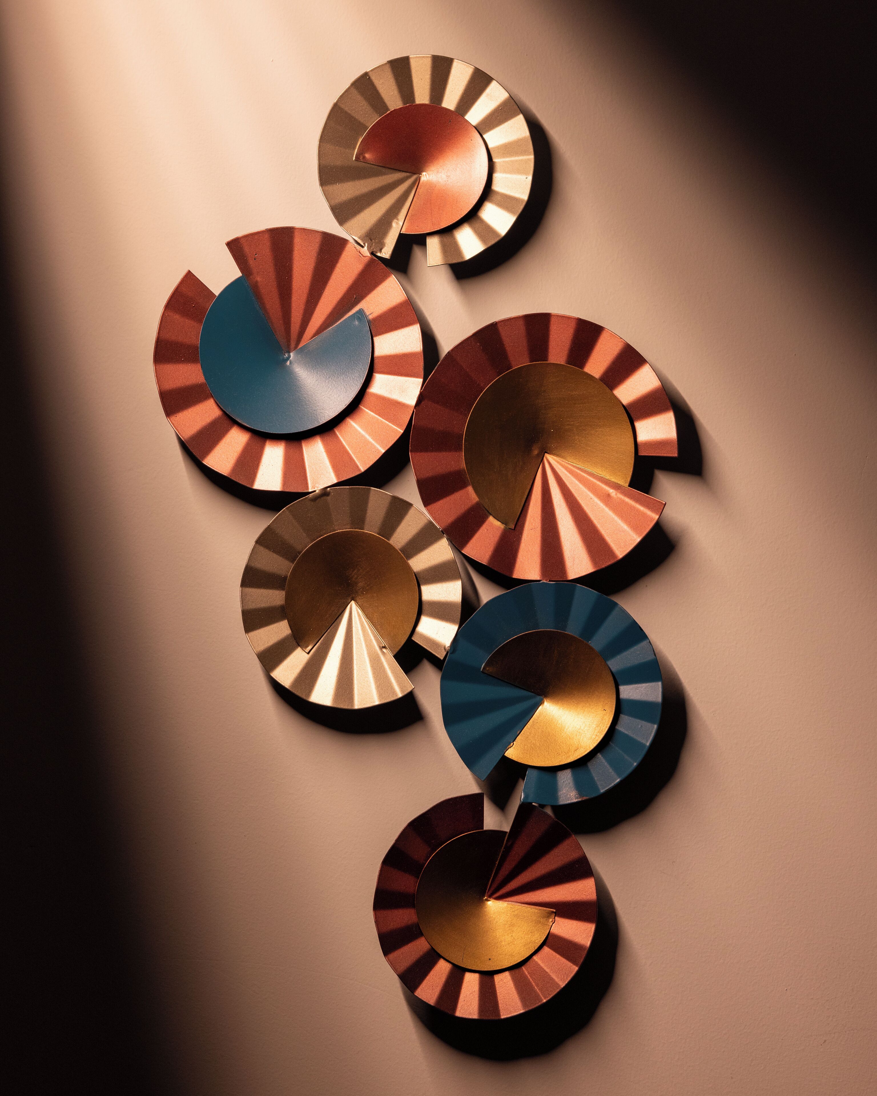 Una obra de arte circular metálica montada en la pared, con un diseño radial.