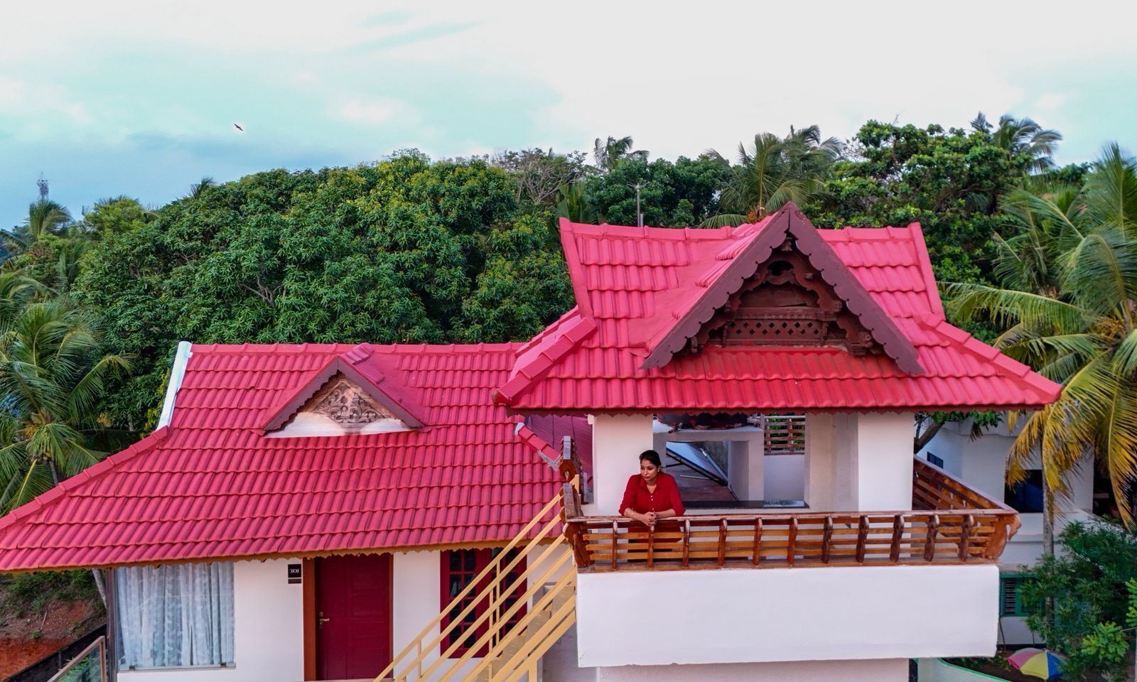 A two-story building with a red roof and a balcony.