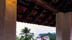 A balcony with a wooden railing, a lantern, and a view of the sea and buildings. - Chechus Beach Walk (Varkala)
