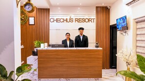 A reception desk at Chechu's Resort with a wooden finish, a clock, and a framed certificate on the wall. - Chechus Beach Walk (Varkala)