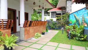 A covered outdoor area with a tiled walkway, columns, and a mural of a temple. - Chechus Beach Walk (Varkala)