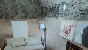 Une petite pièce au décor rustique, avec un canapé, un tapis à motifs et des œuvres d’art accrochées aux murs.