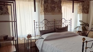 Une chambre à coucher au style rustique, avec un plafond en bois, un cadre de lit en métal, une couvre-lit blanche et une petite table de chevet avec une lampe.