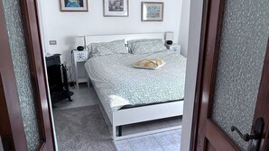 Een slaapkamer met een bed, nachtkastje, lamp en een deur met geëtste glas.