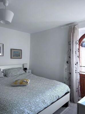A bedroom with a bed, a bedside table, a lamp, and a window with curtains. - Relais Marmore with a Jacuzzi for two, a wood-burning stove in the room, and pets allowed (Ferentillo)