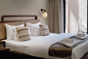 A neatly made bed with white linens, multiple pillows, and a decorative throw blanket.