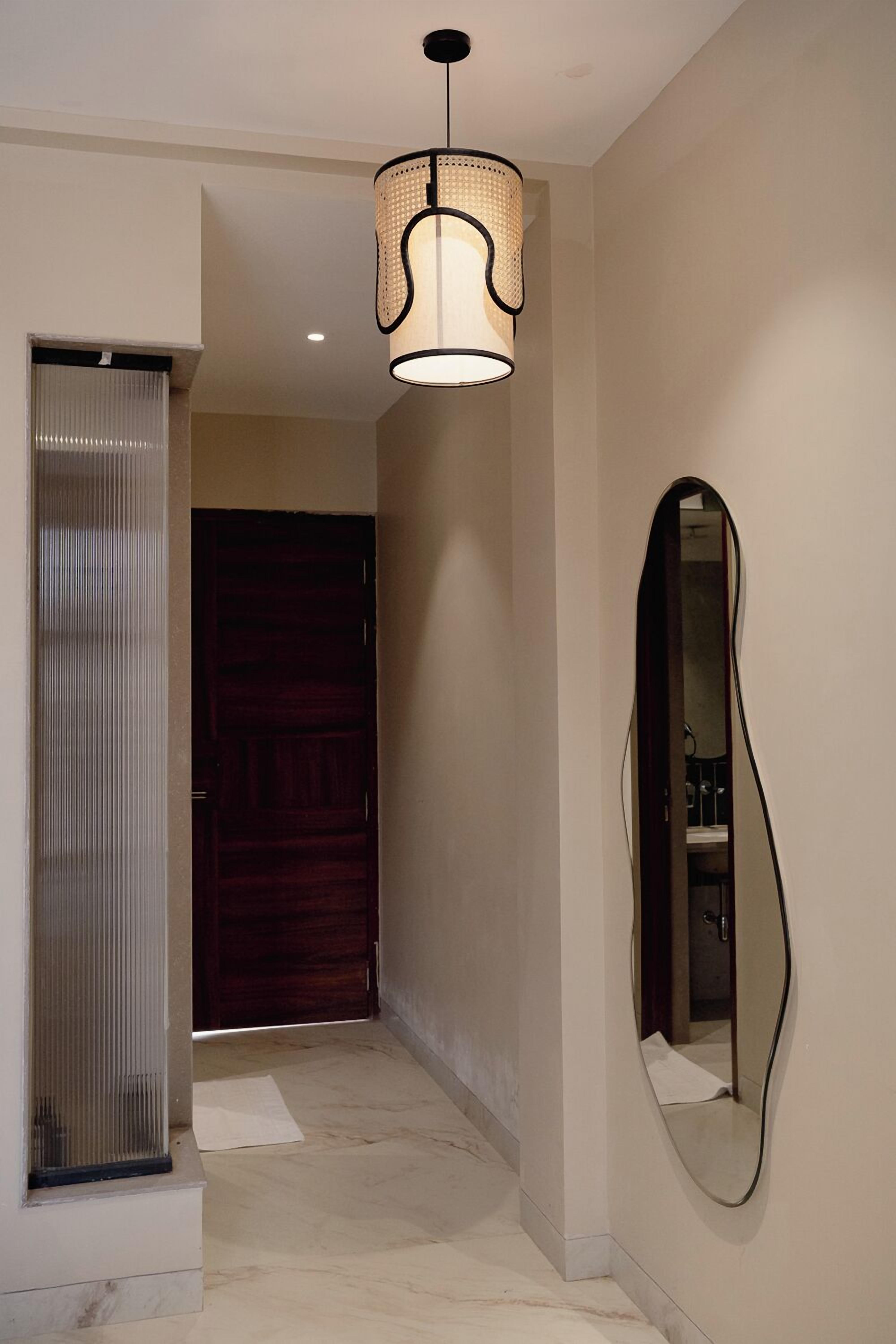A hallway with a wooden door, a mirror, and a hanging light fixture.