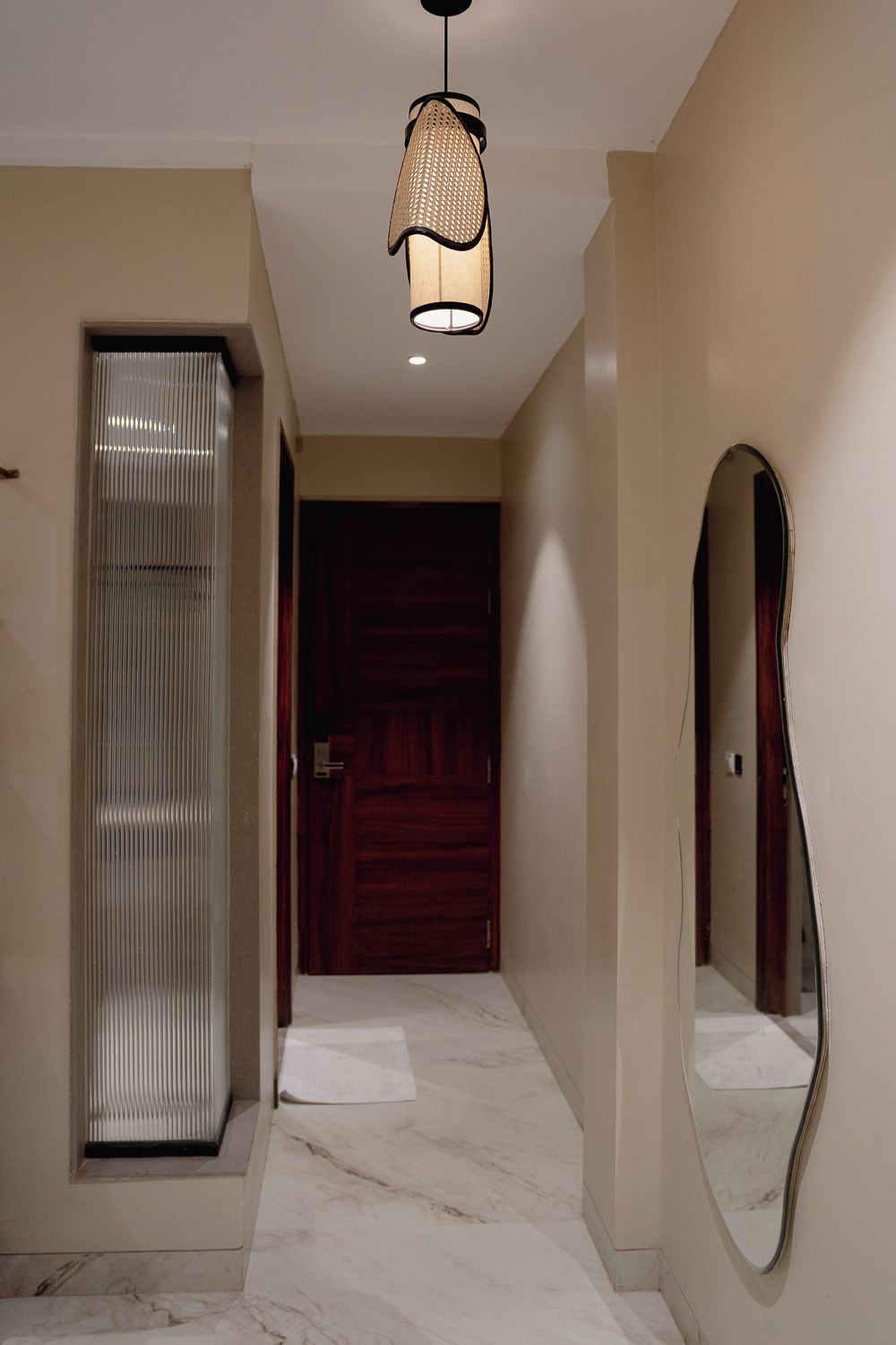 A hallway with a wooden door, a mirror, and a ceiling light fixture.